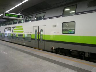 Zeleno-bílá souprava City Airport Train stojí u nástupiště s cedulí CAT.